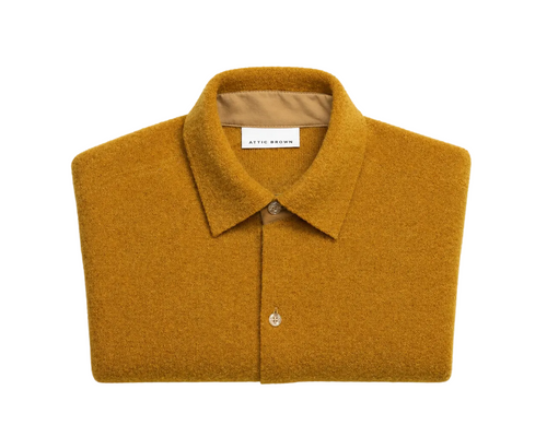Folded mustard yellow shirt with a visible brand label on a light gray background